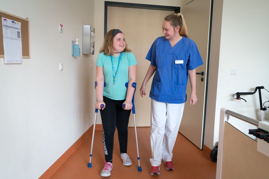Patientin uebt mit Pflegekraft Laufen